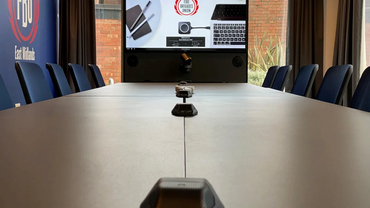 Boundary microphones down a boardroom table, with a video conferencing unit at the end