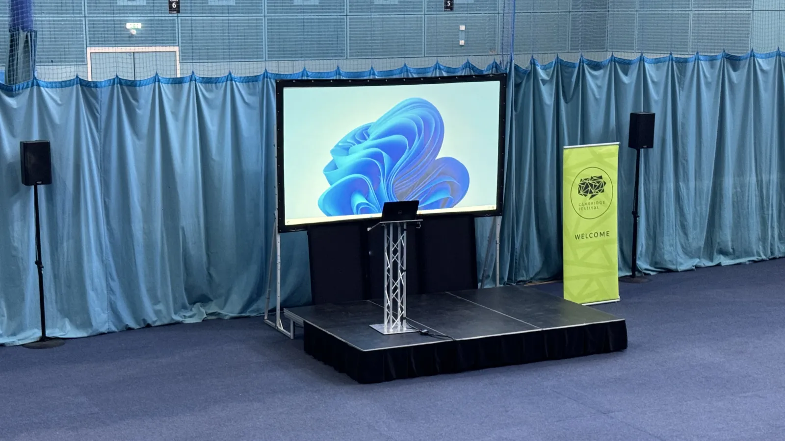 A screen, stage, lectern and speakers hired from AV Xpert for the Cambridge Festival at the University Sports Centre