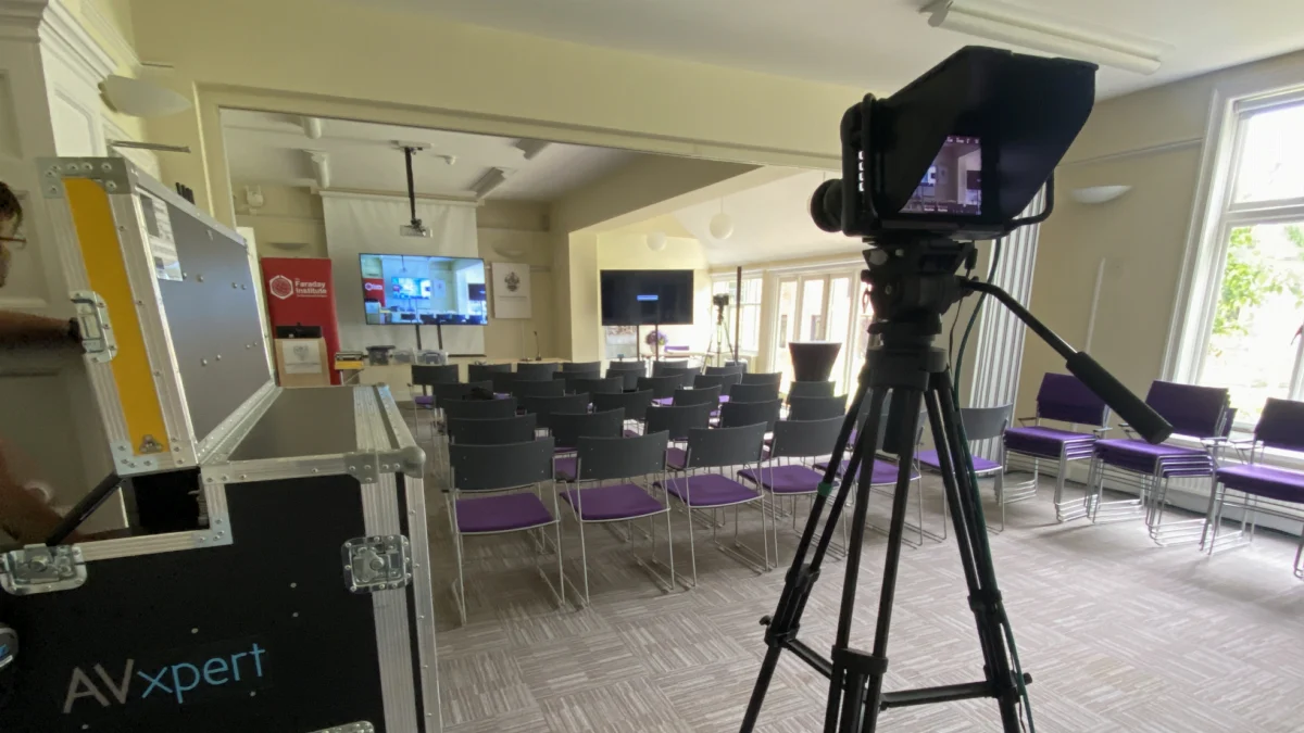 A camera on a tripod beside an AV Xpert flight case at the Faraday Institute