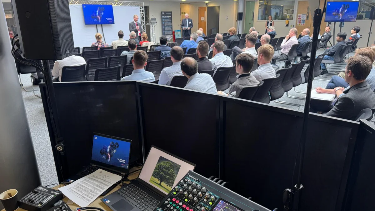 The AV Xpert control desk at a TWI conference, with screens and a speaker on stage