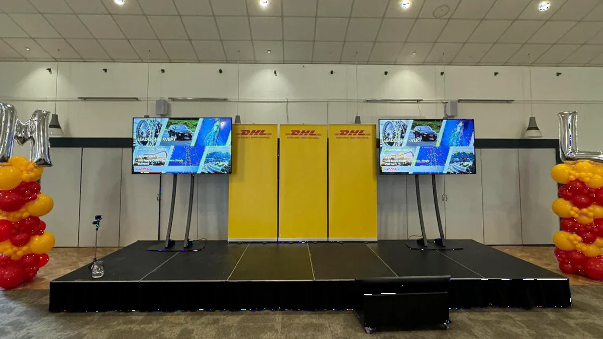 A DHL event stage with branded 75 inch displays