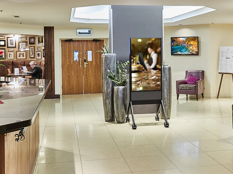 A portable digital signage screen welcoming guests in a hotel reception