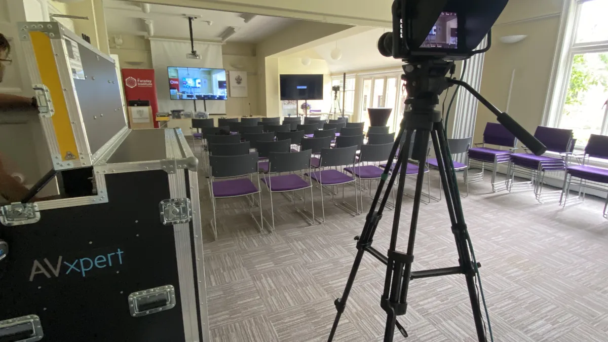 A camera filming a hybrid conference at the Faraday Institute in Cambridge