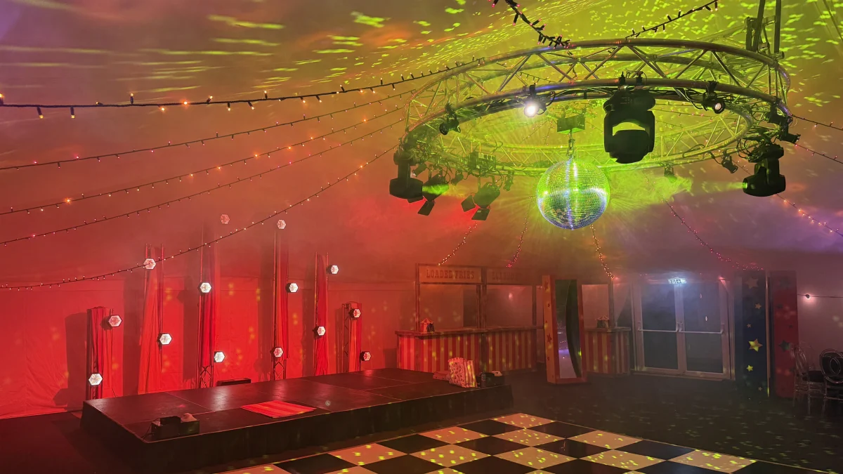 Moving heads and a mirror ball on circular truss over a checkerboard dance floor at a TR Global event