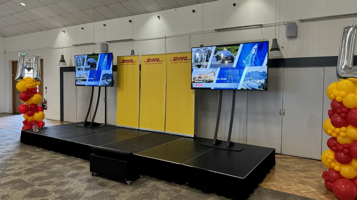 A stage and two screens on stands hired from AV Xpert for a corporate event