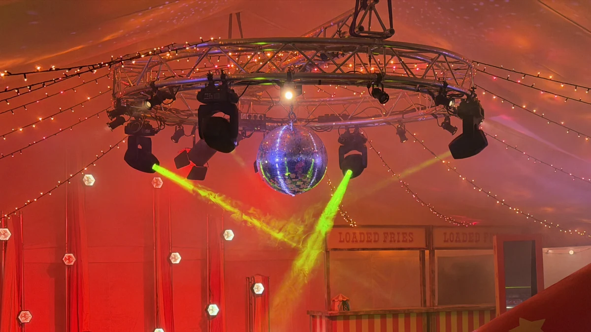 A circle of truss with moving lights and a mirror ball in a marquee for TR Global